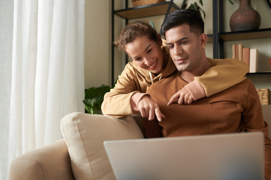 Young couple pointing at laptop as they shop for a Halogen Heater togther