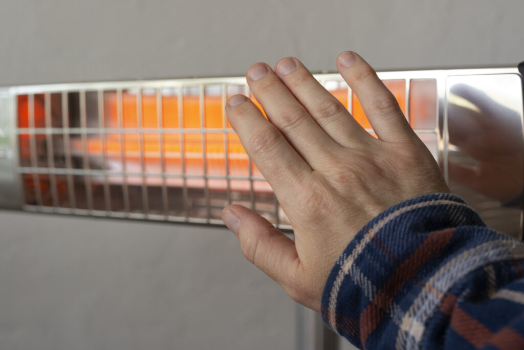 A male warming up hand near checking hisHalogen heater checking for issues